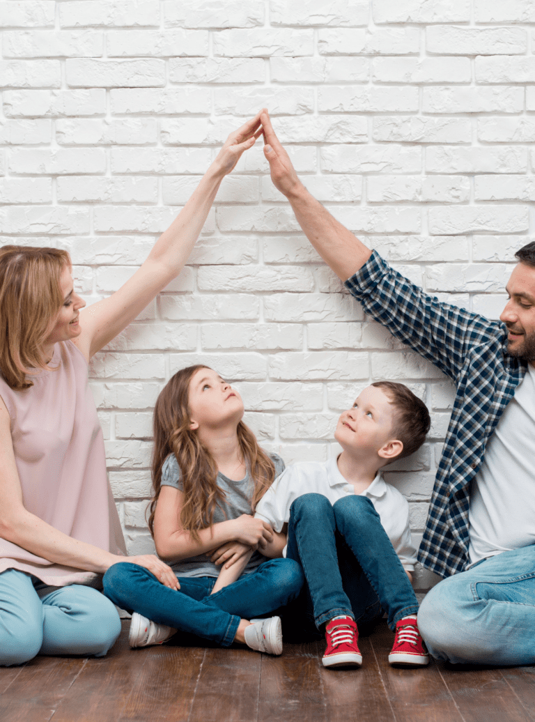 Mother, daughter, son, and father against white brick wall, parents are high fiving each other